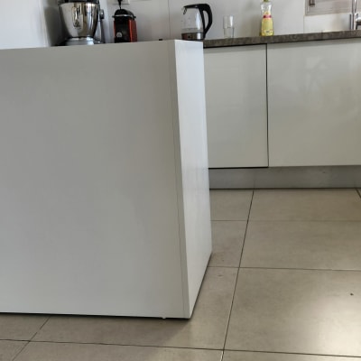 מטבח עם ארונות לבנים, בלנדר ומכונת קפה על השיש