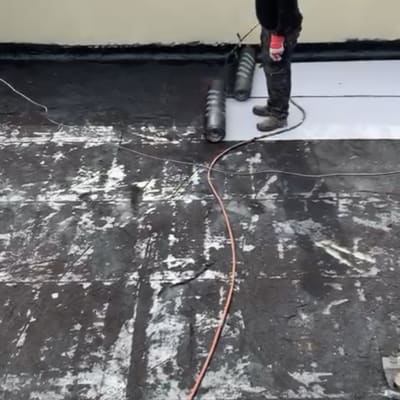 אדם עובד על איטום גג עם יריעות ביטומניות.