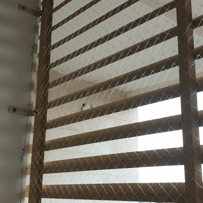 רשת מתוחה על תריסי עץ למניעת כניסת יונים