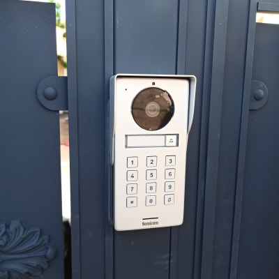 אינטרקום עם מצלמה ומקשים על שער מתכת כחול