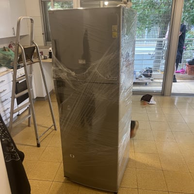 מקרר עטוף בניילון במטבח עם סולם ליד