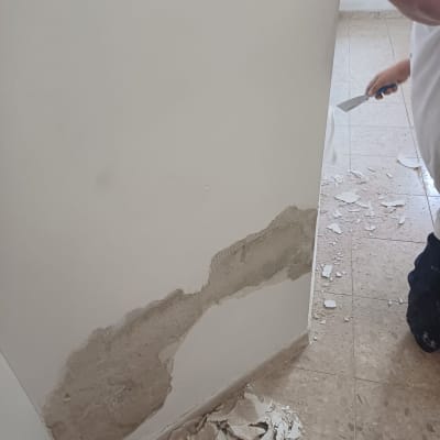 קיר עם טיח מתקלף ואדם עם שפכטל