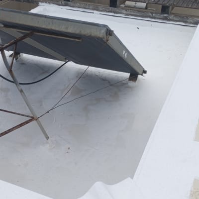 גג אטום עם חומר לבן ליד קולטן שמש