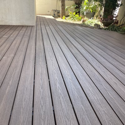 דק עץ חום בגינה עם צמחייה מסביב