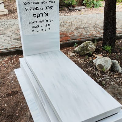 מצבה לבנה עם כיתוב בעברית בבית קברות