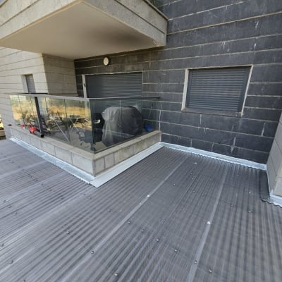מרפסת עם גג פלסטיק שקוף ומעקה זכוכית