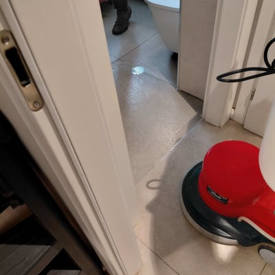 מכונת ניקוי אדומה על רצפה רטובה ליד דלת פתוחה