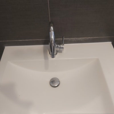 כיור עם ברז כרום על רקע קיר אריחים אפור