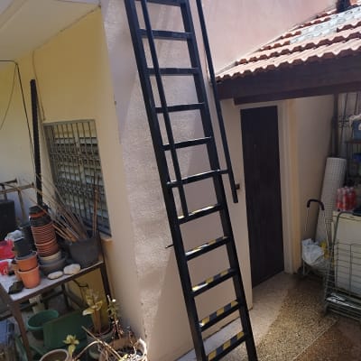 סולם מתכת שחור נשען על קיר חיצוני