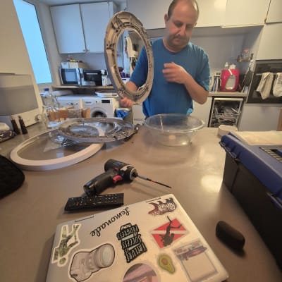 אדם עובד עם כלי עבודה במטבח, כולל מברגה ומחשב נייד