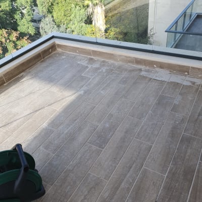 מרפסת עם רצפה מלוכלכת וצינור ירוק לניקוי