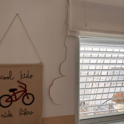 קיר עם סדקים ליד חלון וילון