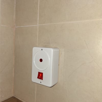 מתג חשמלי עם נורית חיווי אדומה על קיר