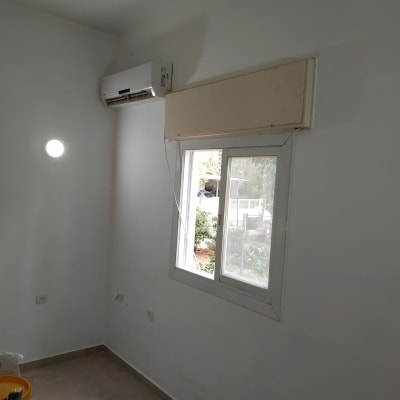 קיר צבוע בלבן עם חלון ומזגן