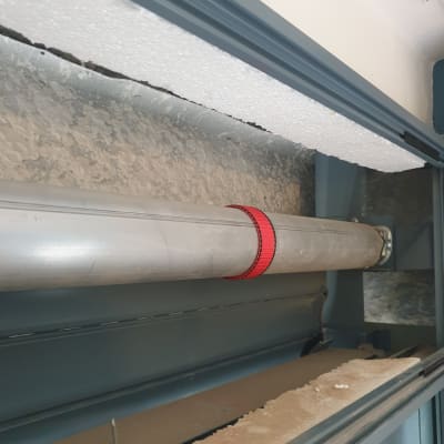 צינור מתכת עם רצועה אדומה בתריס גלילה