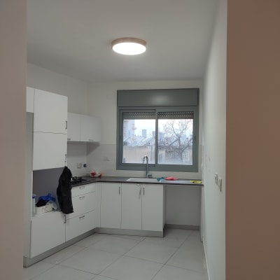 מטבח משופץ עם ארונות לבנים ומשטח עבודה אפור