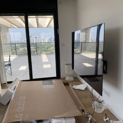 טלוויזיה מותקנת על קיר עם קופסאות וכלים מסביב