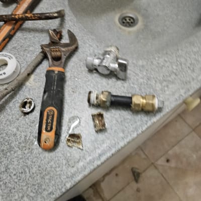 כלי עבודה של אינסטלטור על כיור עם ברזים וחלקים