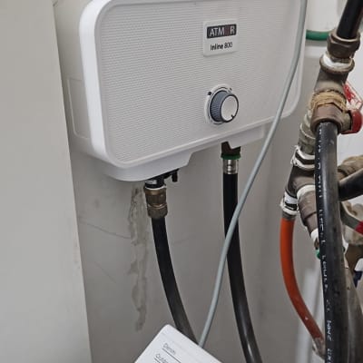 חיבורי צנרת ומכשיר חשמלי ליד מכונת כביסה