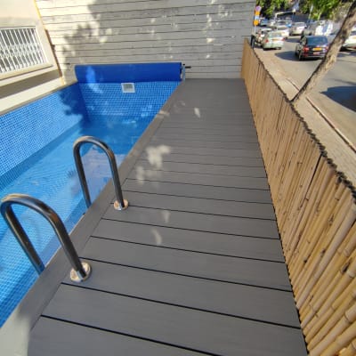 בריכת שחייה עם דק עץ ומעקה מתכת