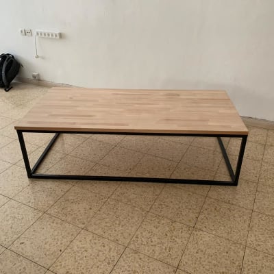 שולחן עץ עם מסגרת מתכת שחורה על רצפה מרוצפת