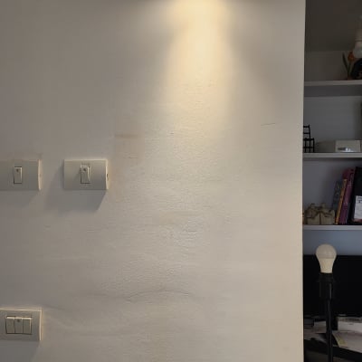 מנורת קיר דולקת ומתגי חשמל על הקיר