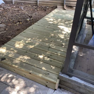 דק עץ חדש ליד חלון זכוכית בגינה