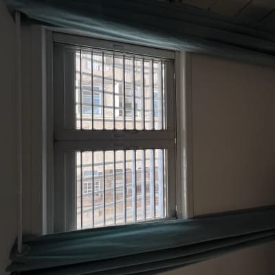 תריסים לבנים עם סורגים על חלון