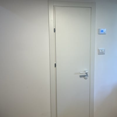 דלת לבנה עם ידית כסופה על קיר לבן