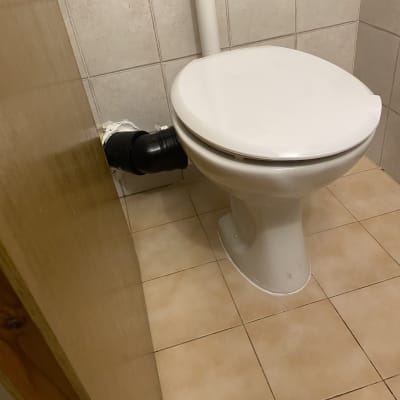 אסלה עם חיבורי צנרת בחדר אמבטיה