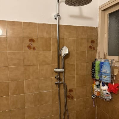 ראש מקלחת וכיור בחדר אמבטיה עם אריחים חומים