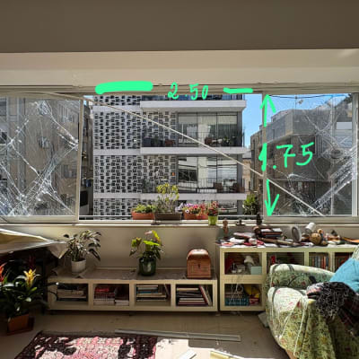 חלון שבור עם מדידות, צמחים וחפצים על מדף