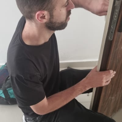 אדם מתקין מנעול בדלת עם מברגים על הרצפה