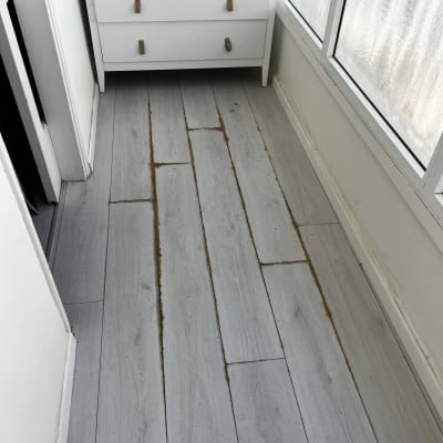 רצפת פרקט עם לוחות פגומים ליד שידה לבנה