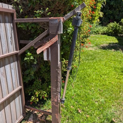 שער חשמלי עם מנגנון פתיחה בגינה ירוקה