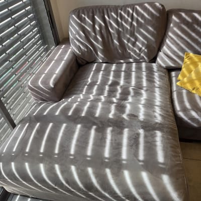 ספה אפורה עם כרית צהובה וצללים מהתריסים