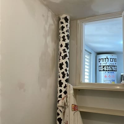 קיר צבוע עם תיקונים, צינור מכוסה בדוגמת פרה, חלון קטן