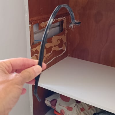 כבל חשמלי שחור מוחזק ביד מול ארון פתוח