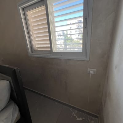 קיר עם חלון פתוח ומיטה לידו