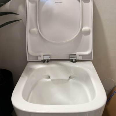 אסלה לבנה עם מכסה פתוח בחדר אמבטיה