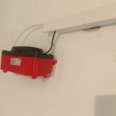 משאבה אדומה מותקנת על קיר עם צינורות חשמל