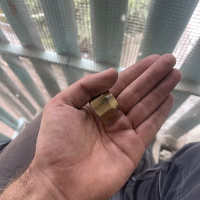 חלק מתכת קטן מוחזק ביד על רקע רשת