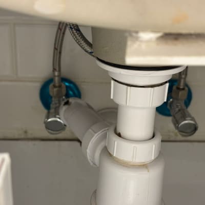 צנרת מתחת לכיור עם חיבורים וכלים