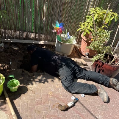 אדם עובד על צינור מים בחצר עם כלי עבודה