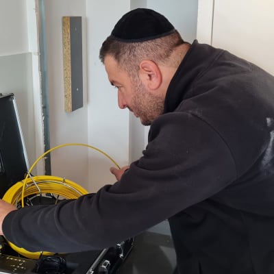 אדם משתמש במצלמה לאיתור נזילות עם מסך ותוף כבלים