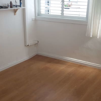 רצפת פרקט עץ בחדר מואר עם חלון ווילון לבן