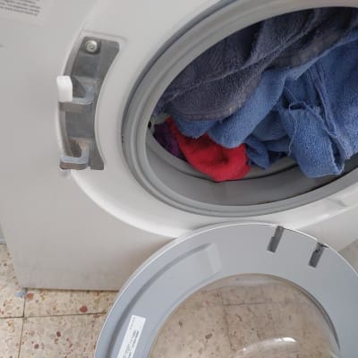 מכונת כביסה עם דלת זכוכית שבורה שמנותקת מהציר