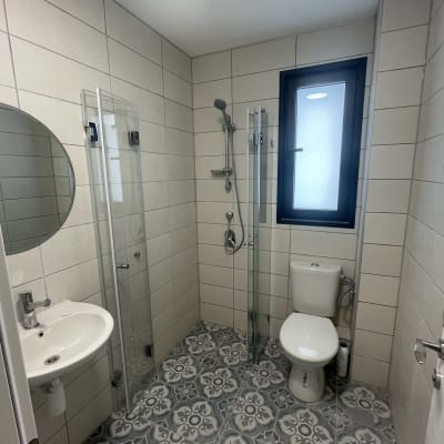 מקלחת עם דלת זכוכית וראש מקלחת כסוף