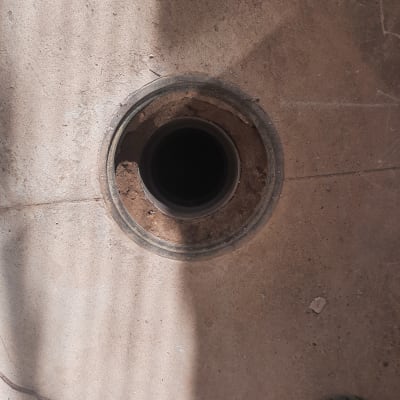 פתח ניקוז עגול ברצפה עם מכסה ירוק בצד