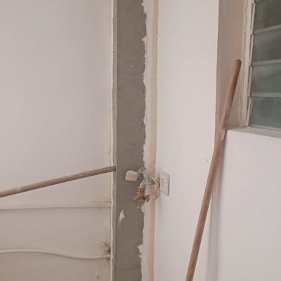 קיר עם טיח חשוף, צינור מים וברז.